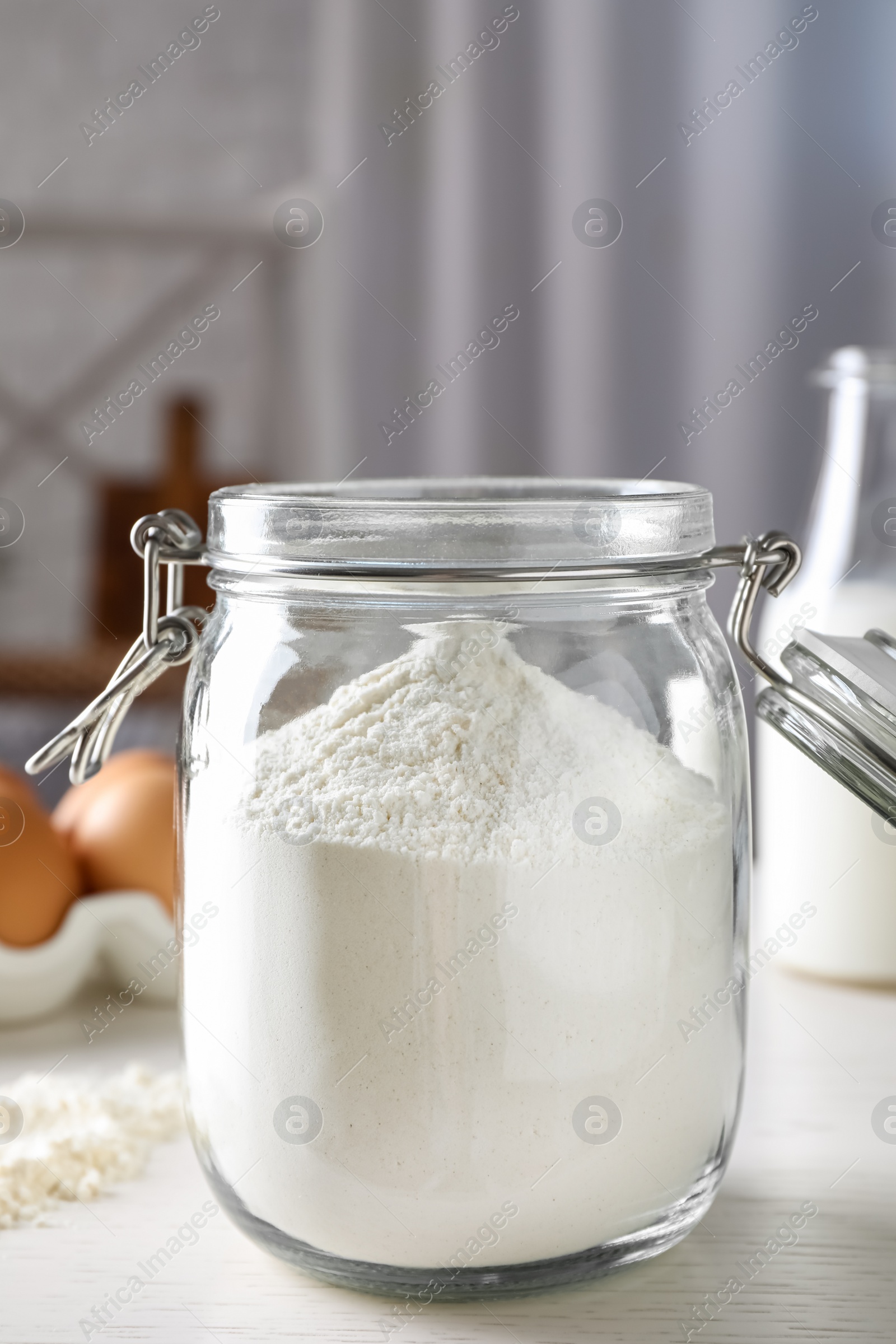 Photo of Glass jar with flour on white table indoors, closeup