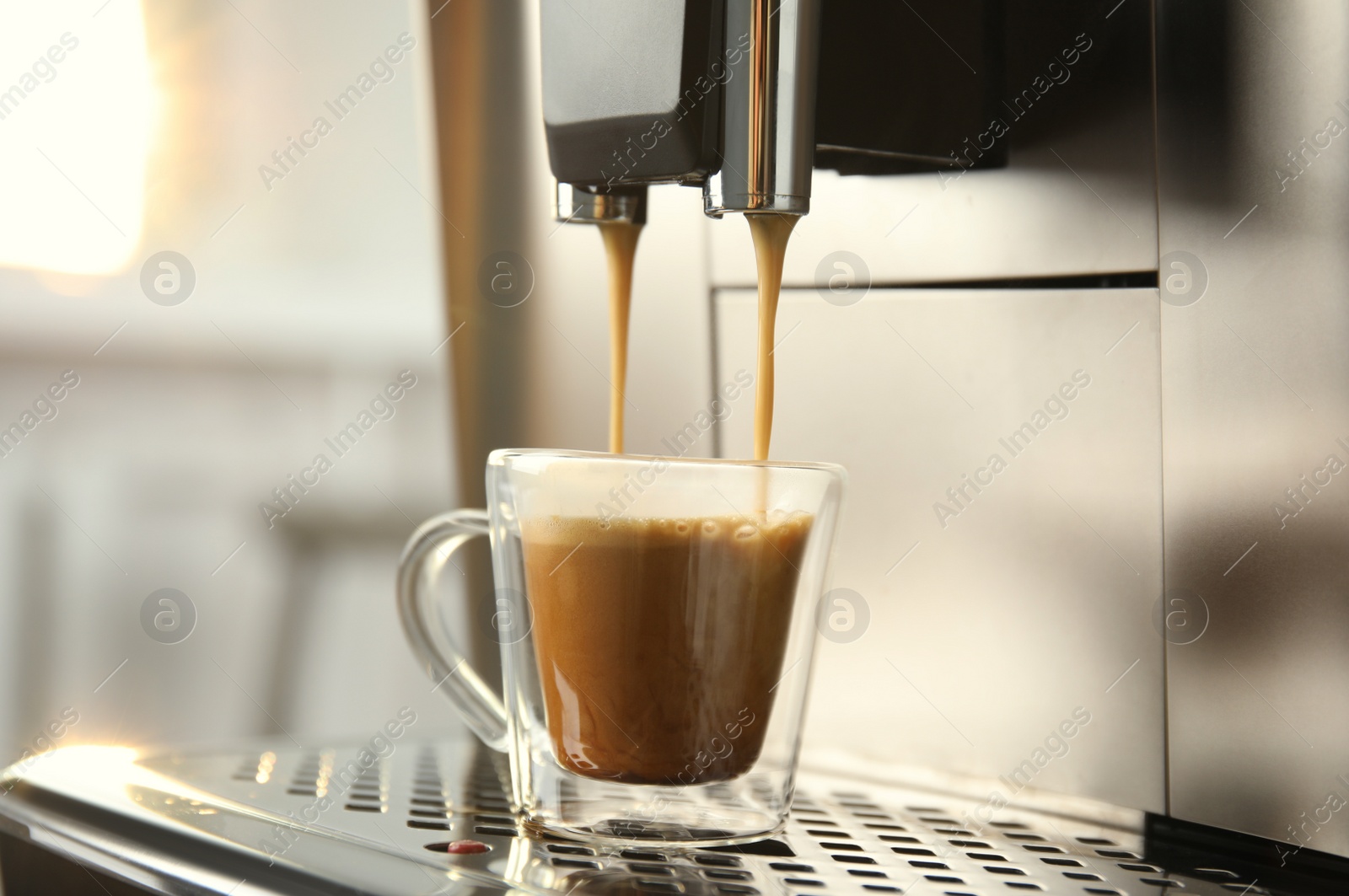 Photo of Espresso machine pouring coffee into glass cup against blurred background, closeup