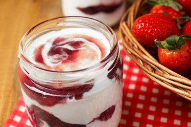 Photo of Tasty yoghurt with jam and strawberries on wooden table, closeup