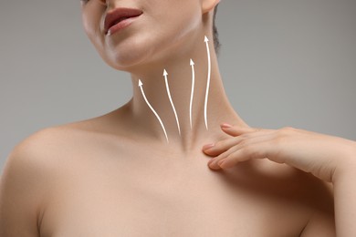 Woman with perfect skin after cosmetic treatment on grey background, closeup. Lifting arrows on her neck and face