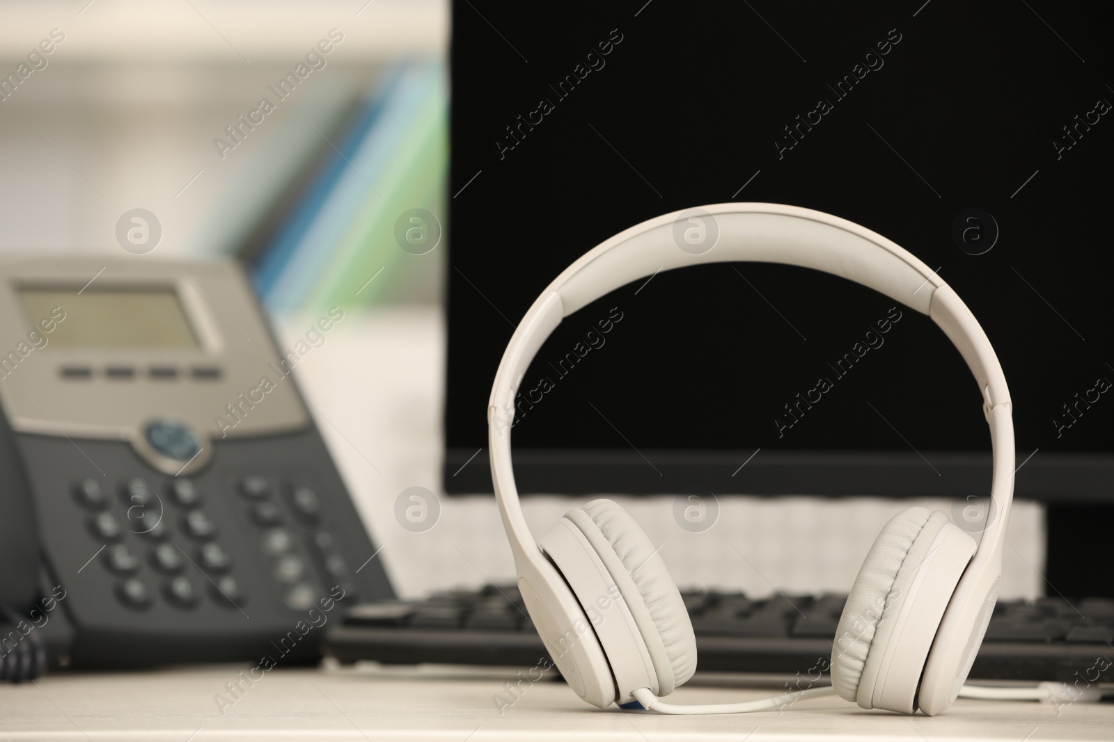 Photo of Modern headphones, desktop telephone and computer on table indoors, space for text