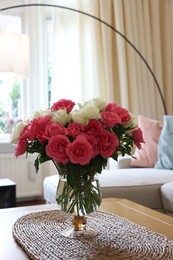 Vase with beautiful bouquet of roses on wooden table at home