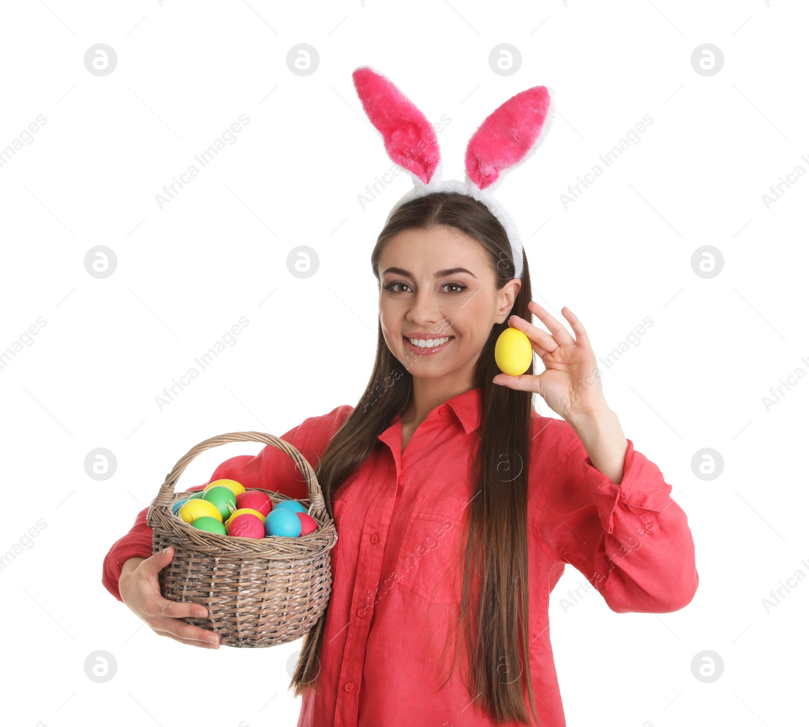 Photo of Beautiful woman in bunny ears headband holding basket with Easter eggs on white background