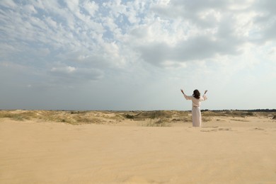Photo of Jesus Christ raising hands in desert, back view. Space for text