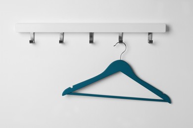 Rack with empty blue clothes hanger on white wall