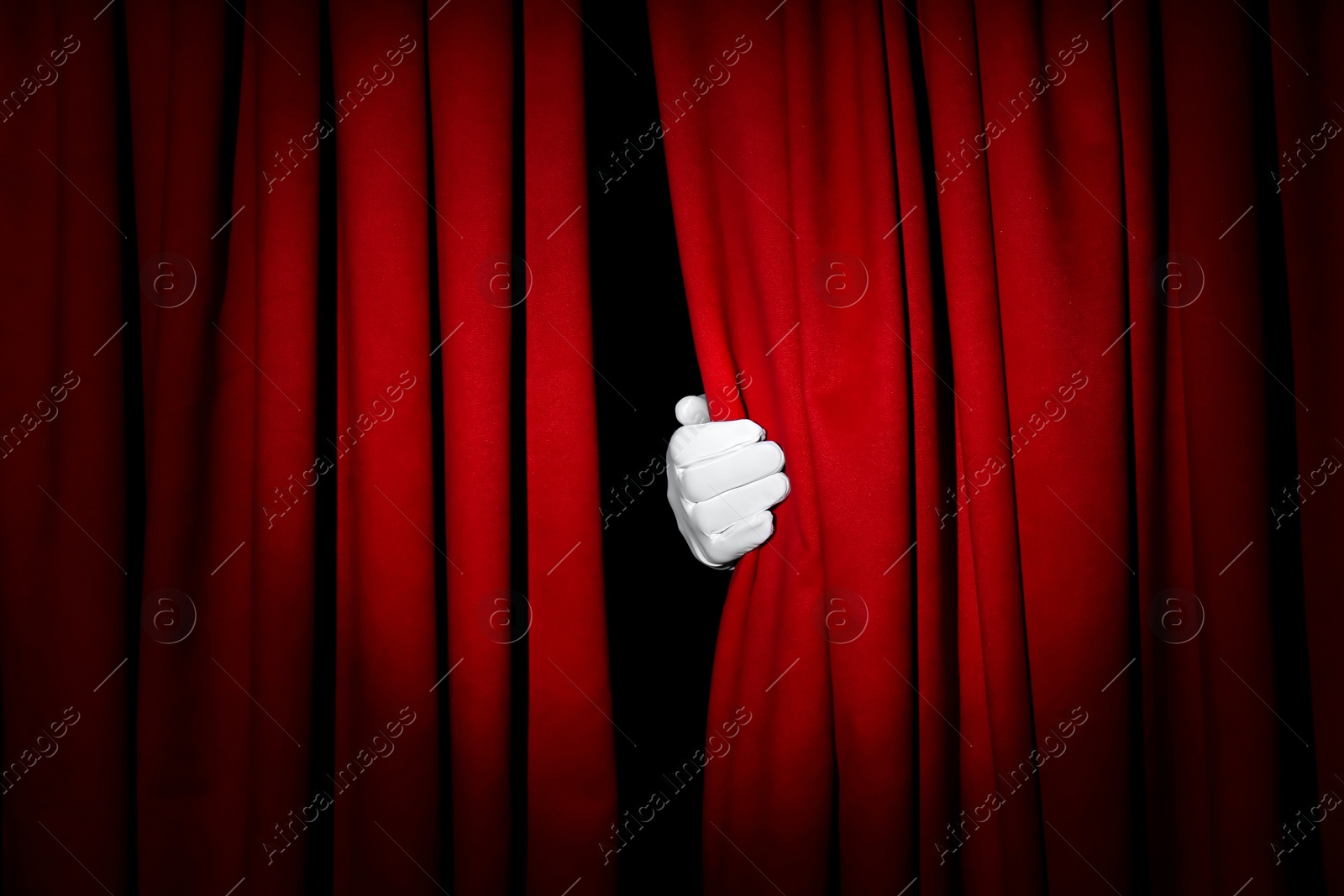 Photo of Person opening red front curtains on black background, closeup