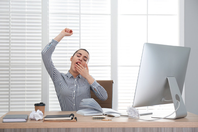 Photo of Lazy employee stretching at table in office