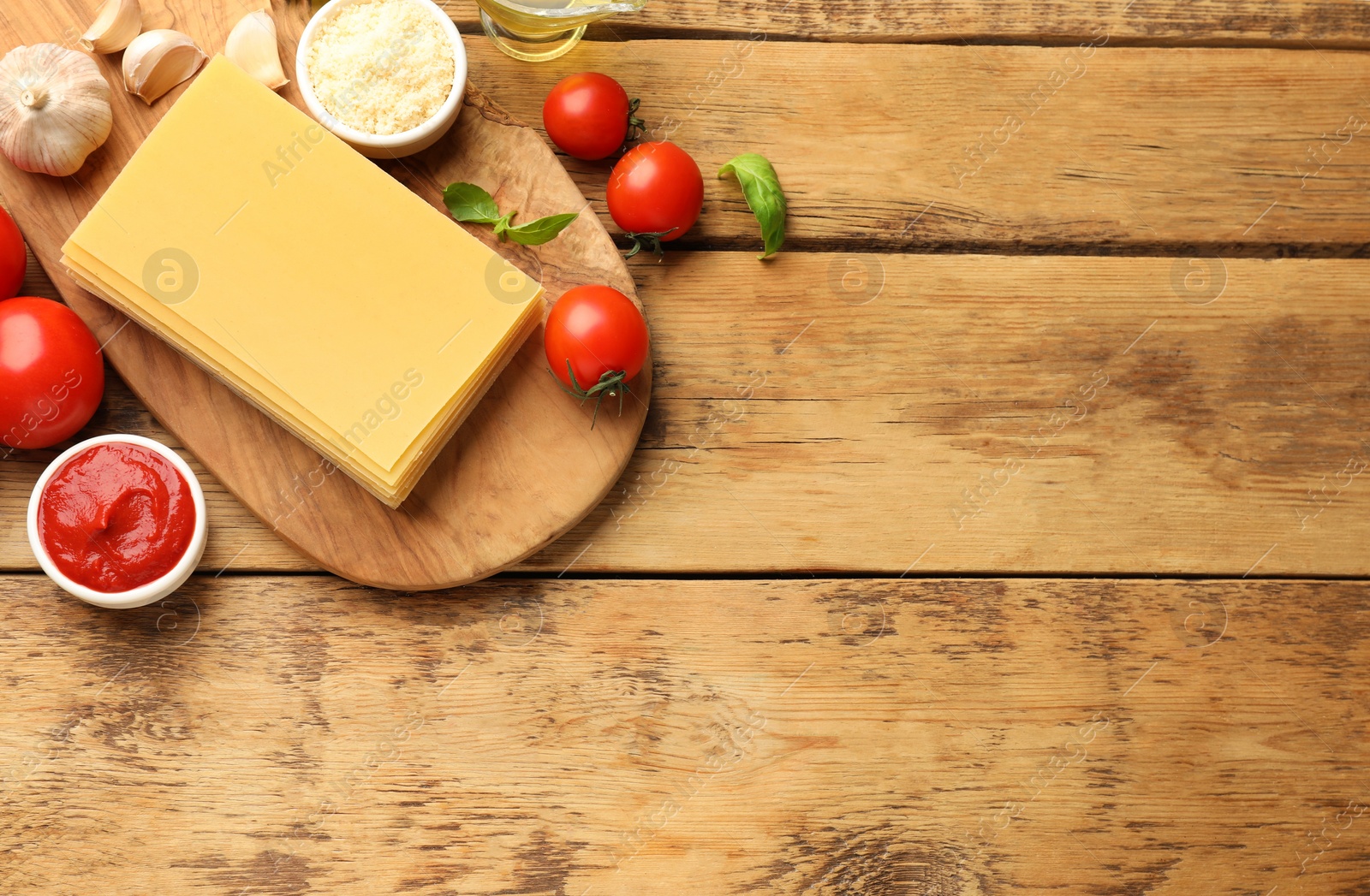 Photo of Flat lay composition with products for cooking lasagna on wooden table. Space for text