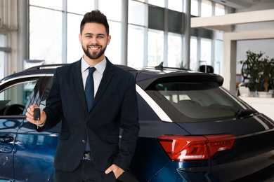 Salesman with key near car in dealership