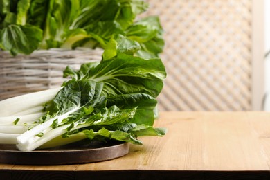 Photo of Leaves of fresh green pak choy cabbage on wooden table, space for text