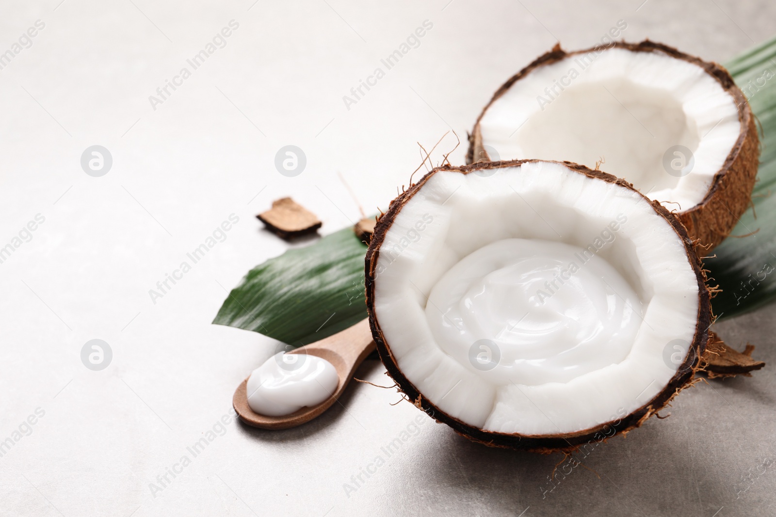 Photo of Ripe coconut and cream on light grey table. Space for text