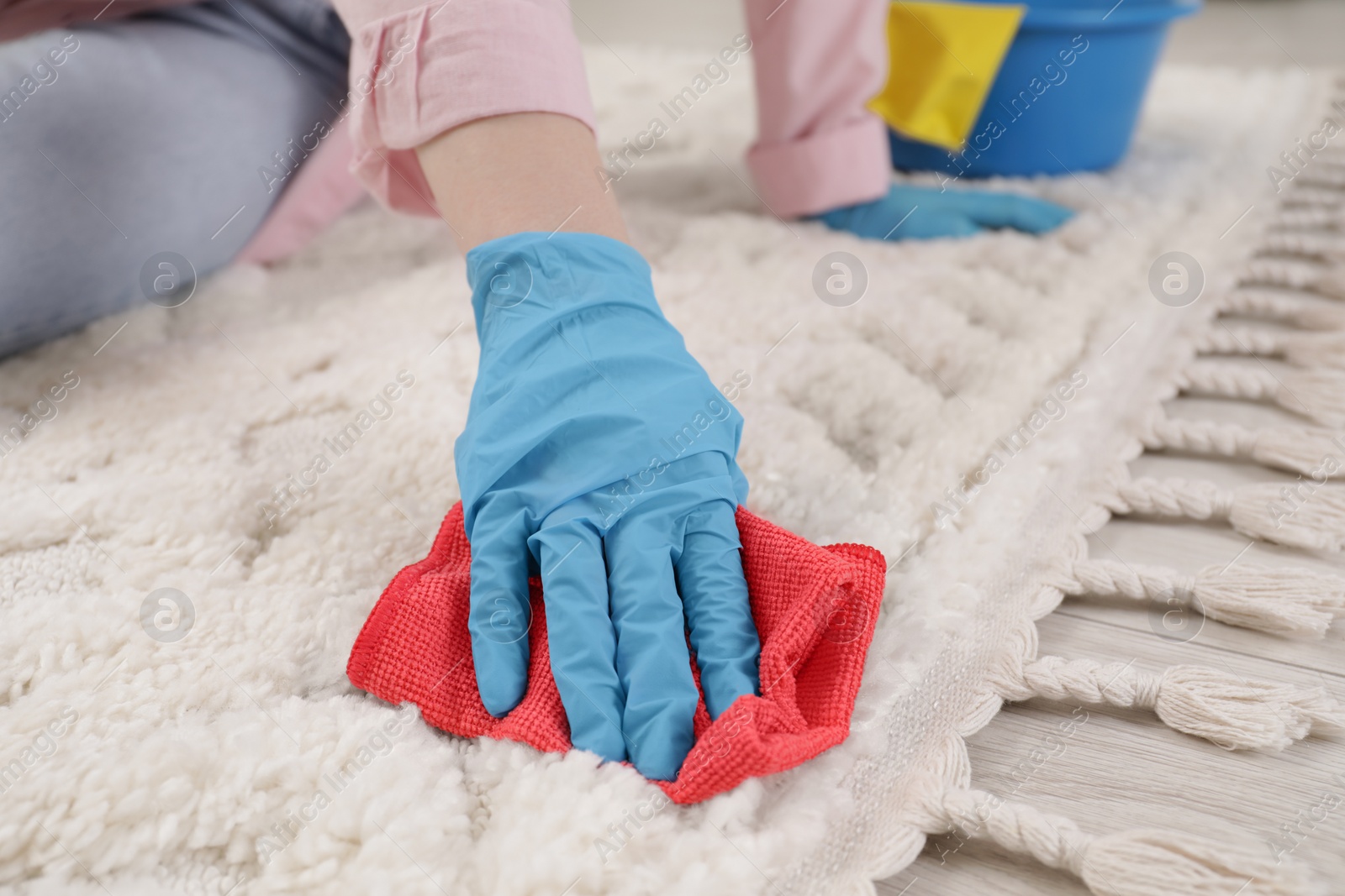 Photo of Woman in rubber gloves cleaning carpet with rag, closeup