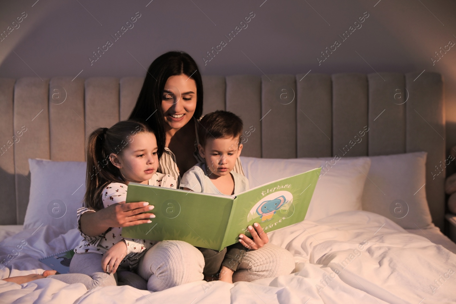 Photo of Mother reading bedtime story to her children at home