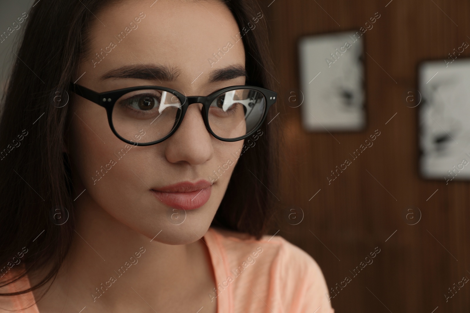 Photo of Beautiful young woman wearing glasses on blurred background. Ophthalmologist service