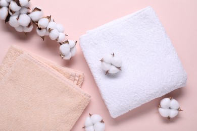 Cotton branch with fluffy flowers and terry towels on beige background, flat lay