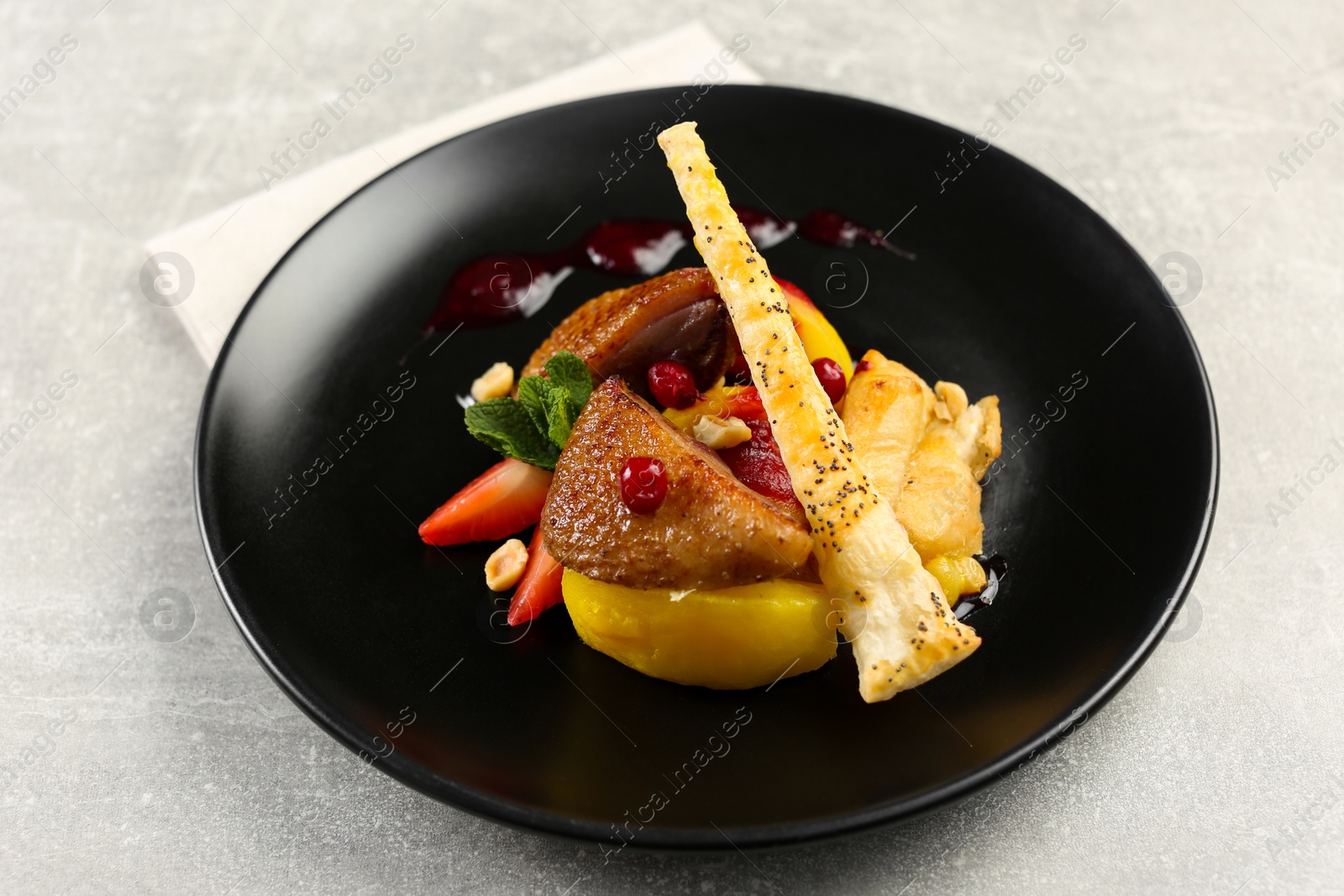 Photo of Plate with delicious chicken, parsnip and strawberries on grey table. Food stylist