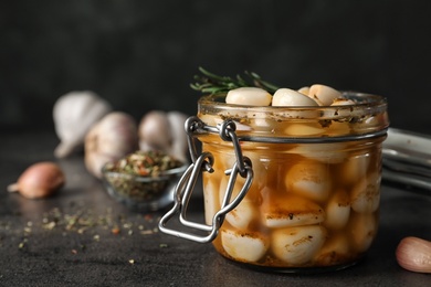 Photo of Preserved garlic in glass jar on table, closeup. Space for text