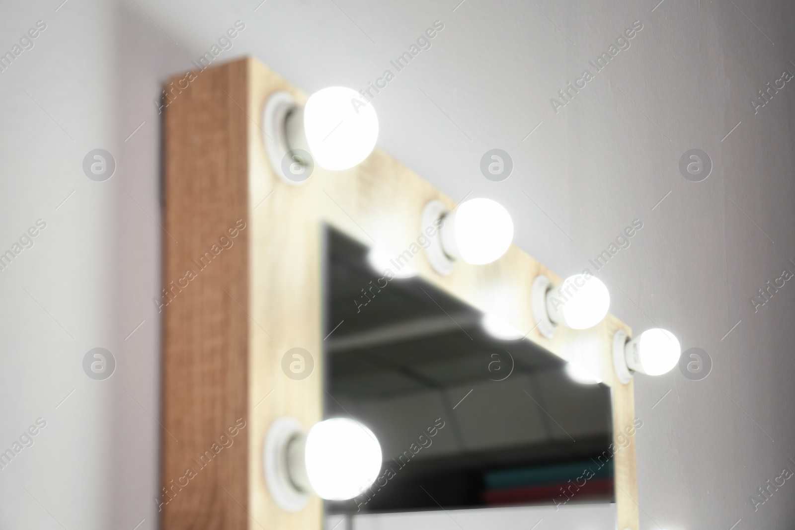 Photo of Mirror with light bulbs on white wall, closeup. Dressing room