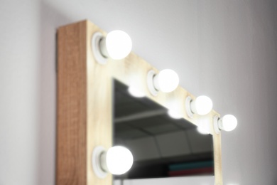 Mirror with light bulbs on white wall, closeup. Dressing room