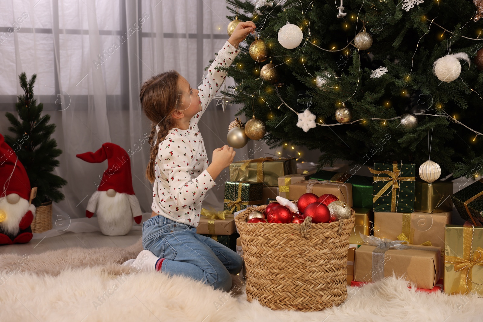 Photo of Cute little child decorating Christmas tree at home