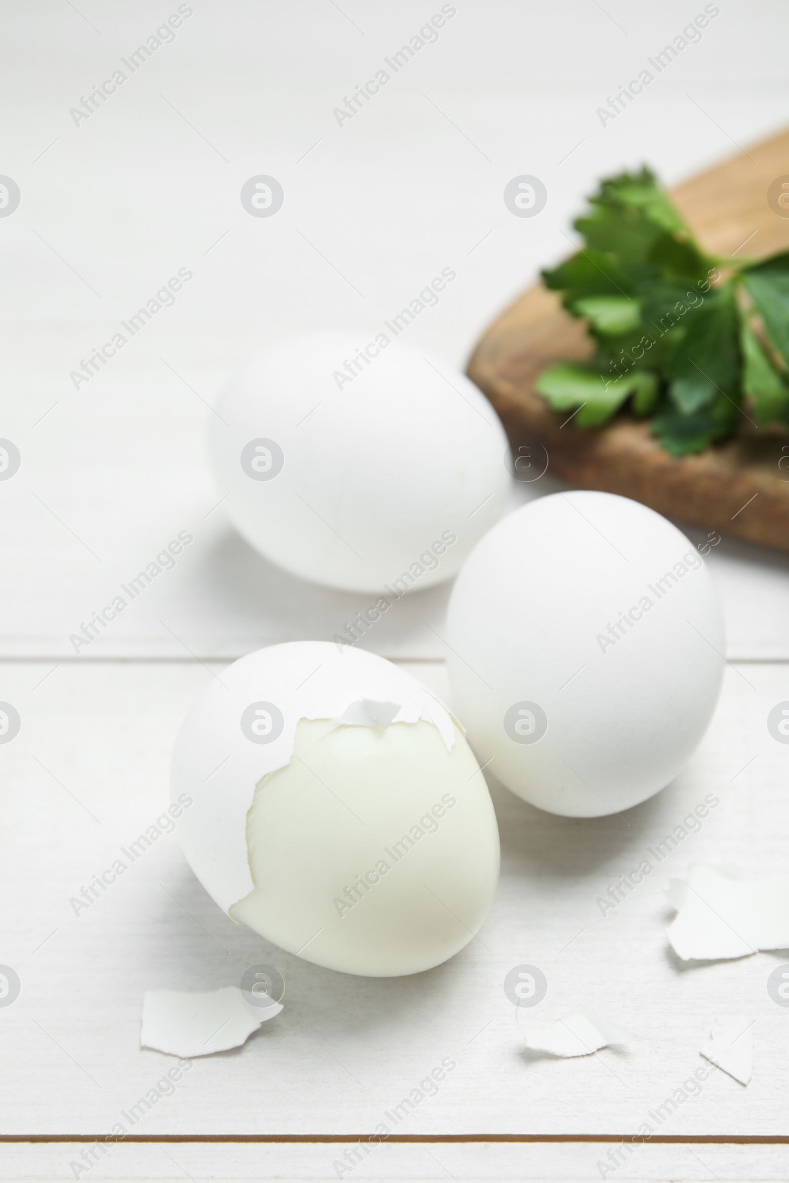 Photo of Boiled eggs and pieces of shell on white wooden table