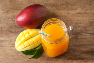 Photo of Mason jar of delicious mango drink on wooden table