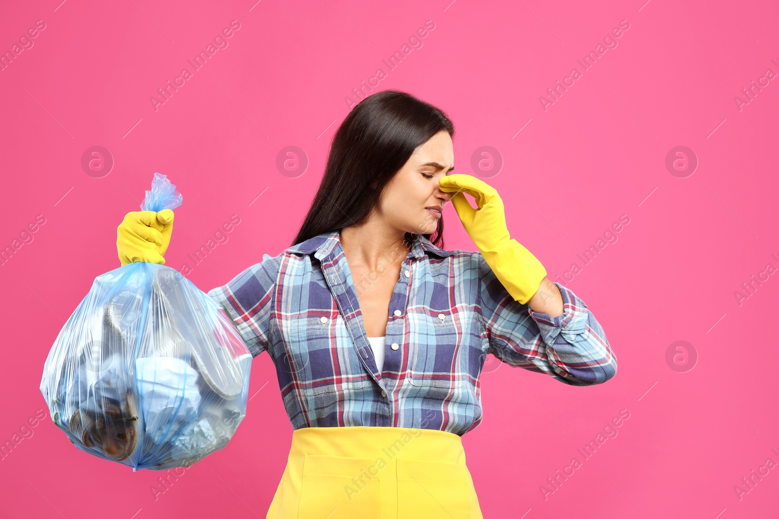 Photo of Woman holding full garbage bag on pink background