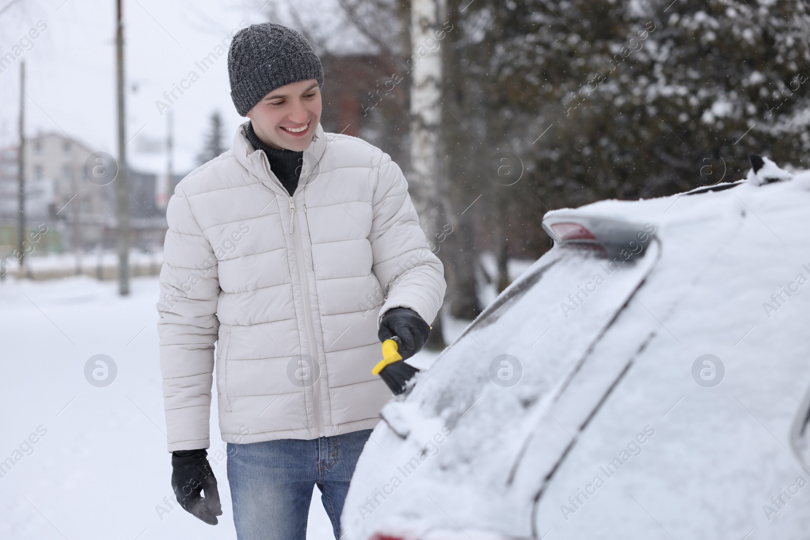 Photo of Man cleaning snow from car window outdoors