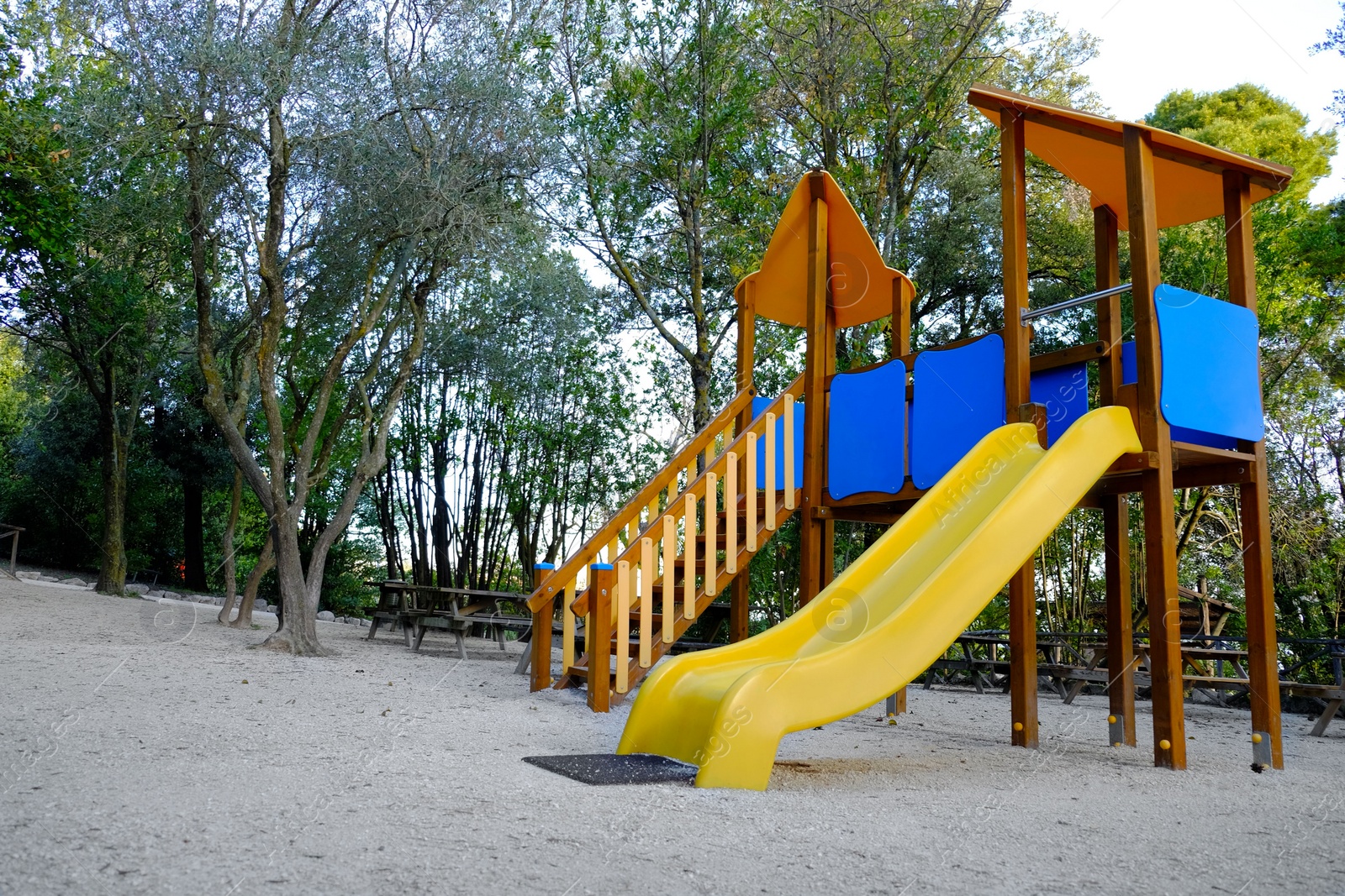 Photo of Empty playground with beautiful slide, benches and trees in park. Space for text