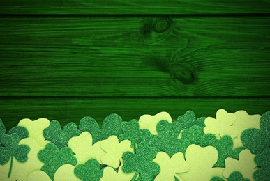 Image of Decorative clover leaves on green wooden background, flat lay with space for text. St. Patrick's Day celebration