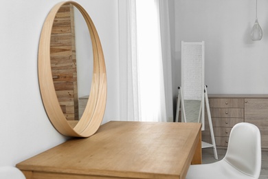 Photo of Makeup room interior with wooden table and mirror near white wall