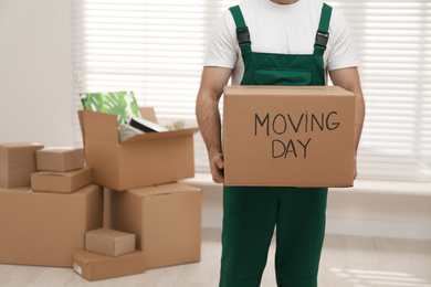 Photo of Man holding cardboard box with words MOVING DAY in room, closeup