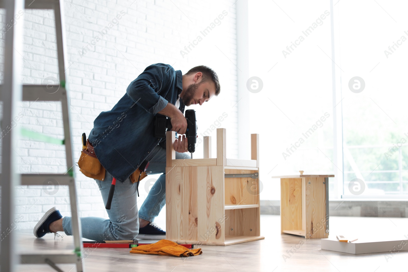 Photo of Young man working with electric screwdriver indoors. Space for text