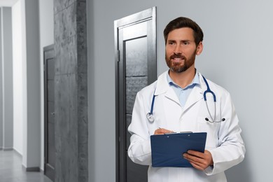 Photo of Doctor in white coat with stethoscope and clipboard indoors. Space for text