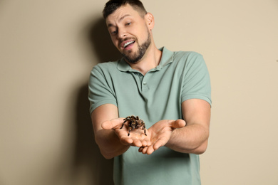 Photo of Scared man holding tarantula on beige background. Arachnophobia (fearspiders)