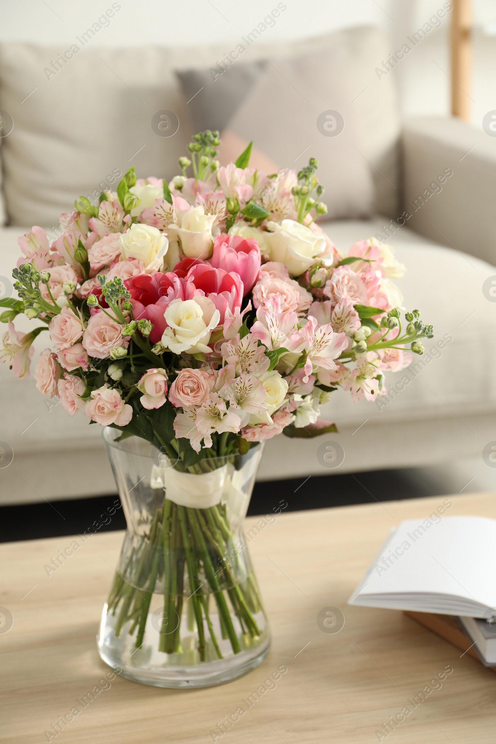 Photo of Beautiful bouquet of fresh flowers in vase on wooden table indoors