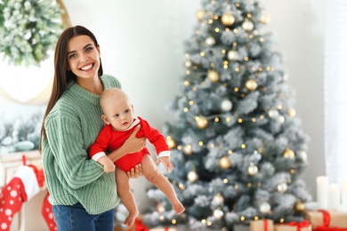 Photo of Mother with her cute baby at home, space for text. Christmas celebration