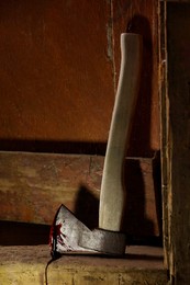 Photo of Axe with blood on wooden threshold indoors