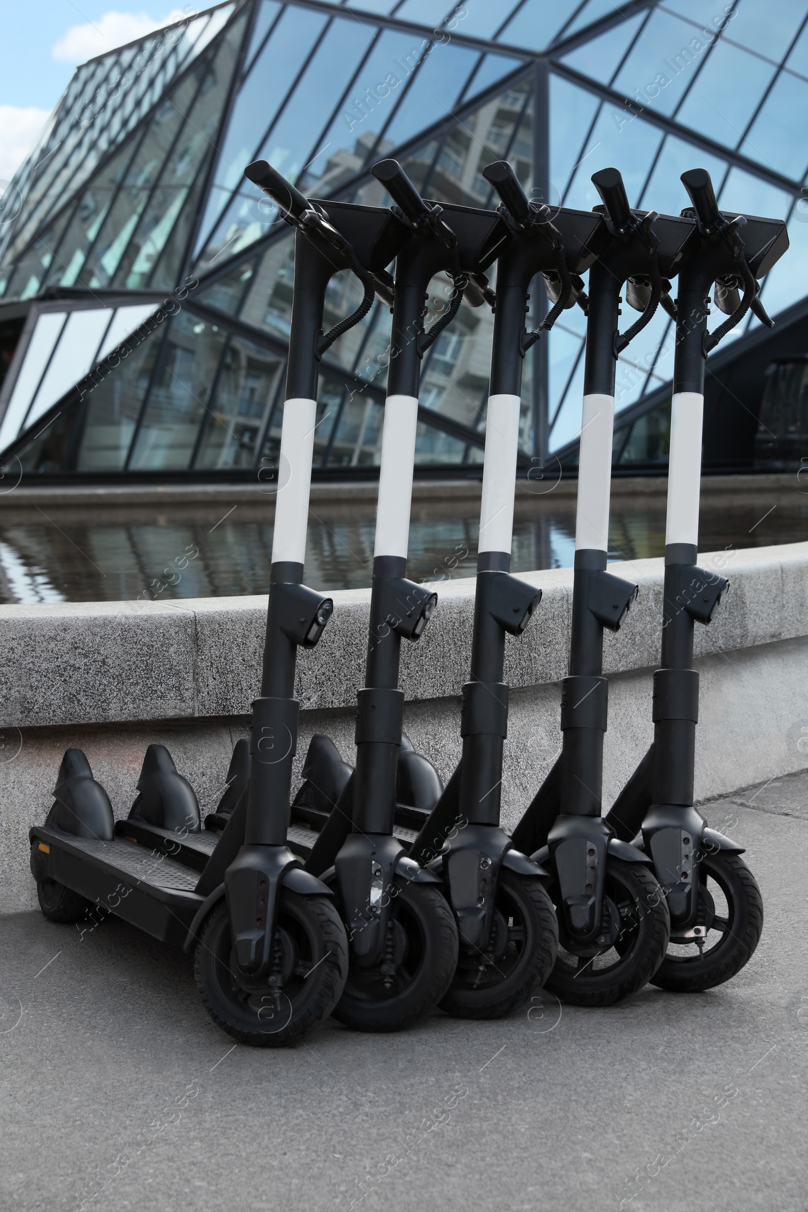 Photo of Row of electric scooters on city street. Rental service