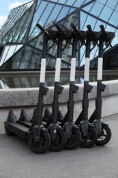 Row of electric scooters on city street. Rental service