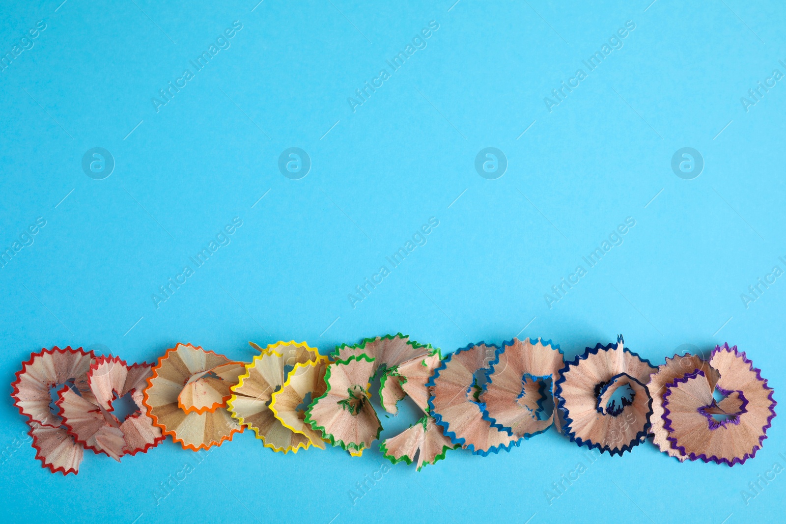 Photo of Pencil shavings on blue background, top view. Space for text