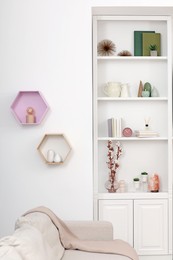 Stylish shelves with decorative elements and sofa. Interior design
