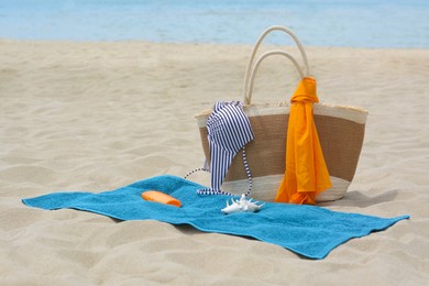 Photo of Blue towel, bag and beach accessories on sandy seashore