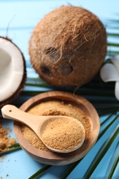 Coconut sugar, palm leaves and fruits on light blue wooden table, closeup