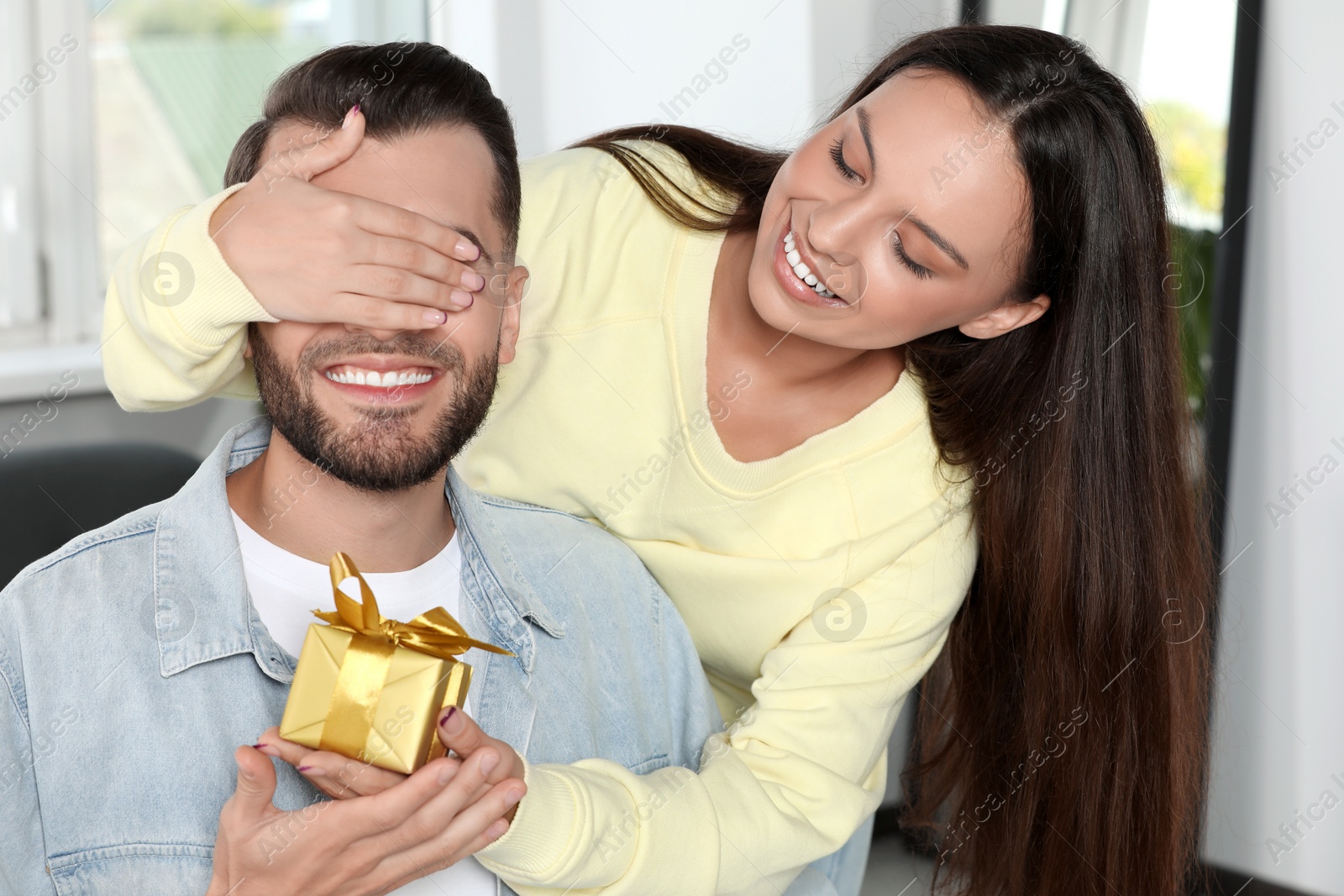 Photo of Woman presenting gift to her boyfriend at home