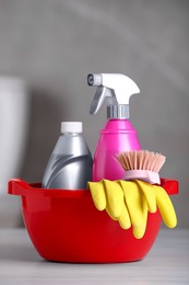Photo of Plastic basin with cleaning supplies on table in bathroom
