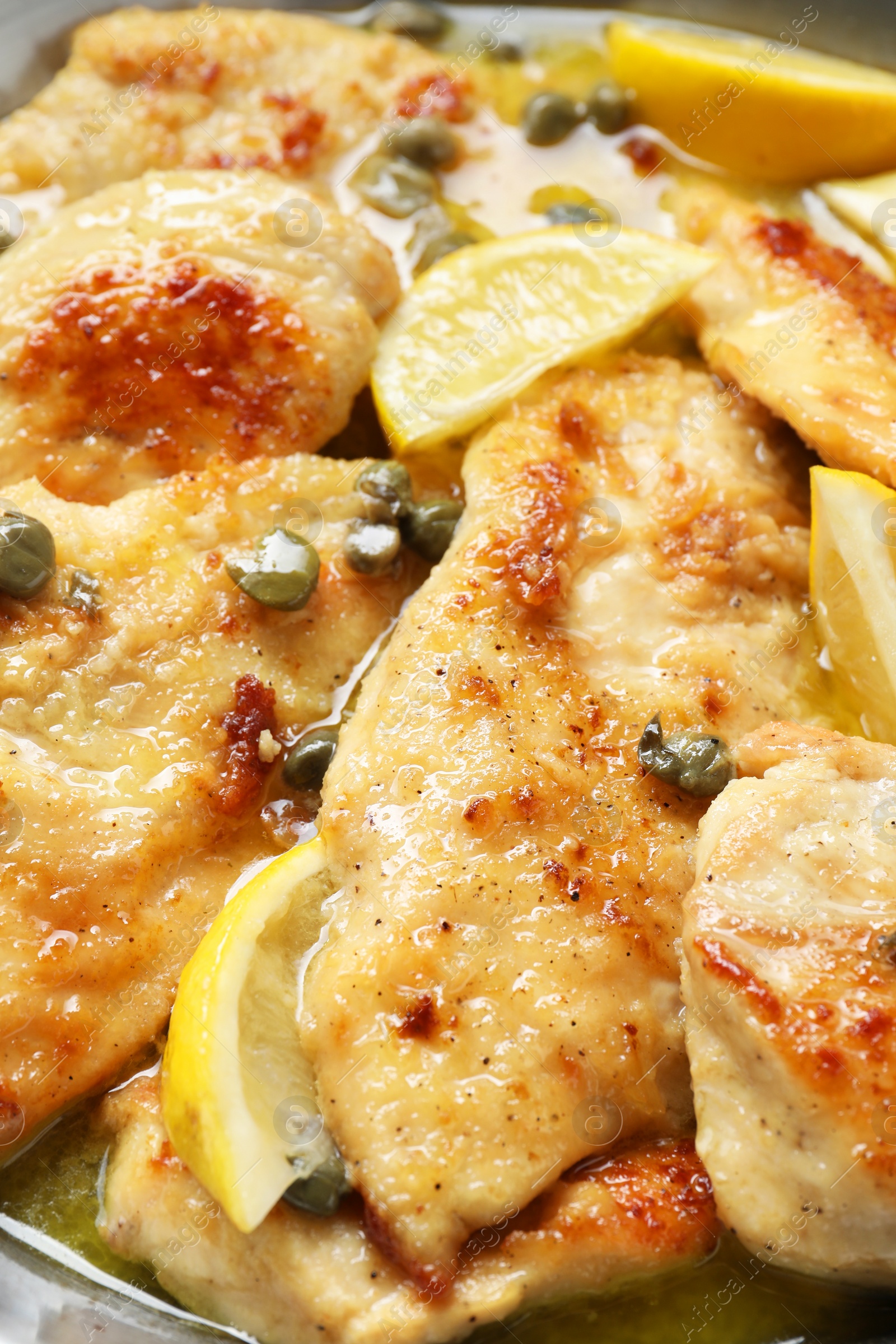 Photo of Delicious chicken piccata with lemons in pot, closeup