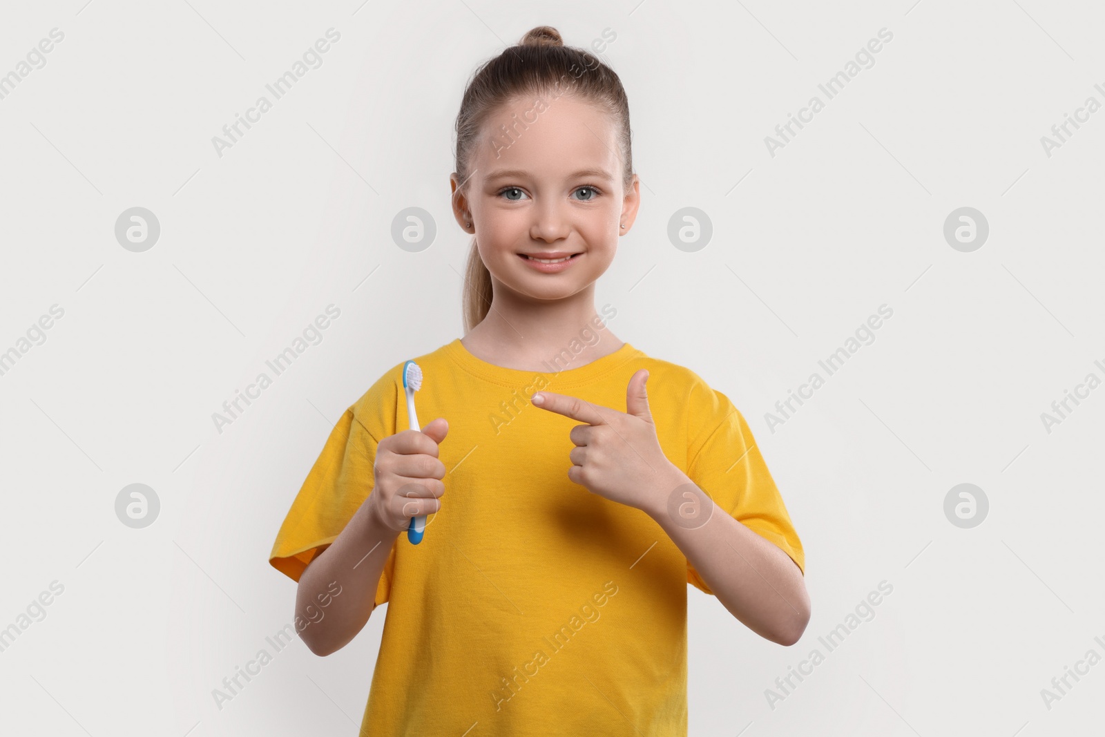 Photo of Happy girl holding toothbrush on white background