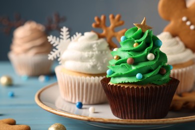 Tasty Christmas tree cupcake on light blue wooden table, closeup view. Space for text