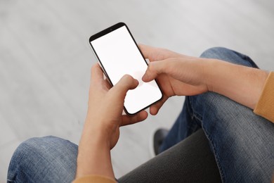 Photo of Man with smartphone on sofa indoors, closeup